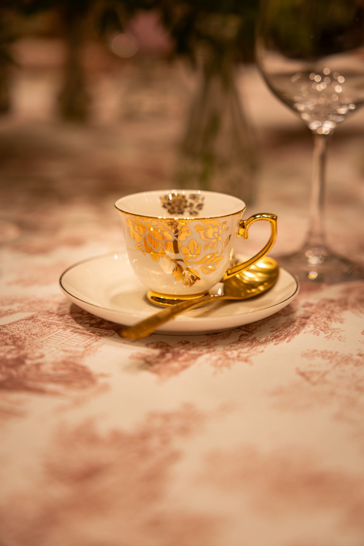Taza de té dorada sobre mantel de toile rosa