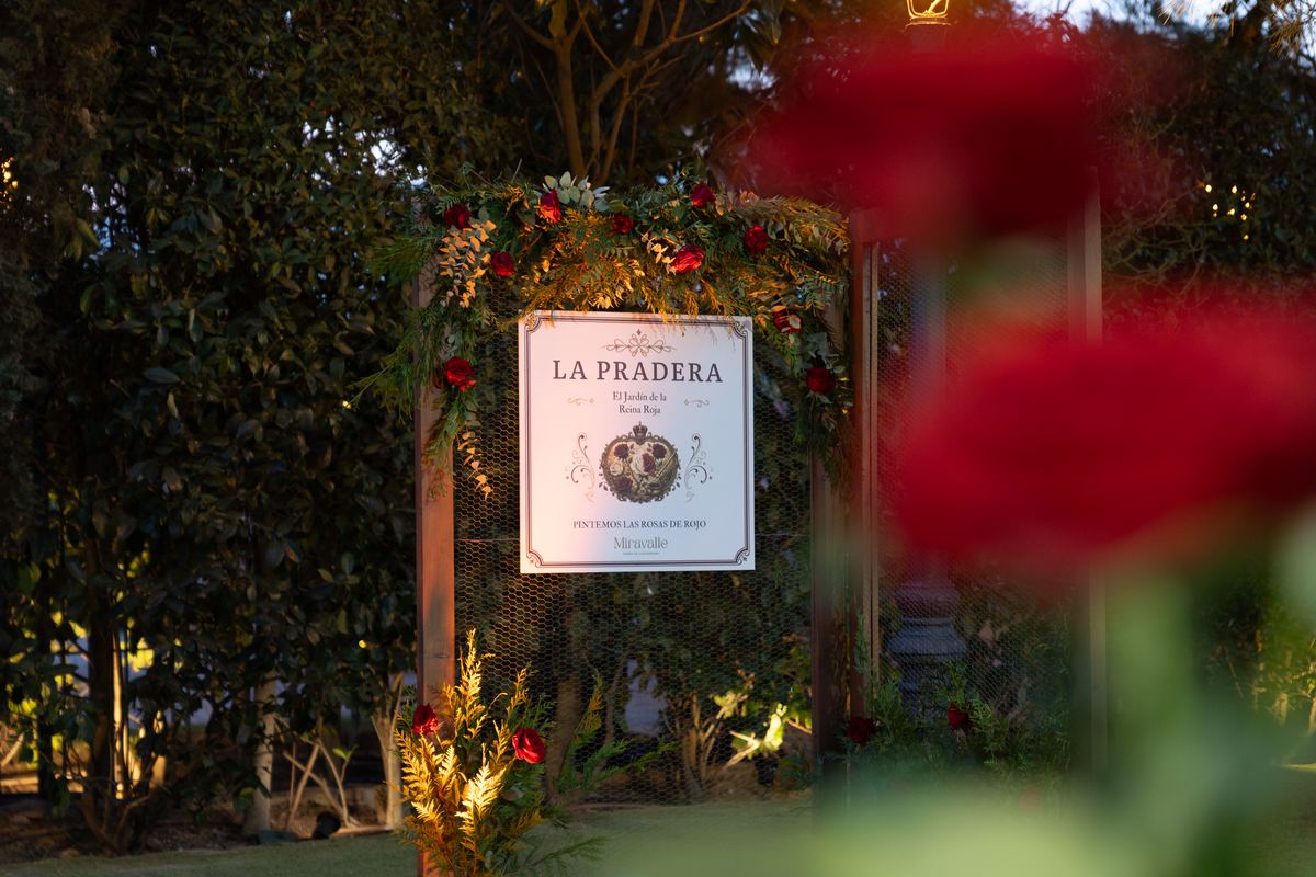 Cartel de La Pradera entre rosas rojas